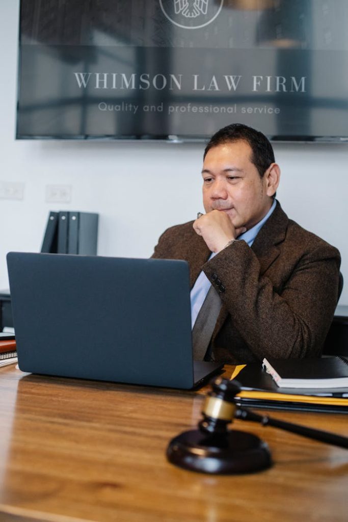 pexels-photo-5668775 Thoughtful Asian lawyer browsing laptop in law office